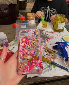 a young boy sitting at a table with sprinkles on his phone case