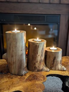 three wooden candles sitting on top of a table next to a fire place in front of a fireplace