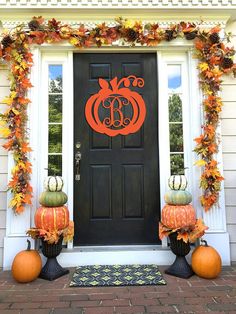 the front door is decorated with pumpkins and leaves