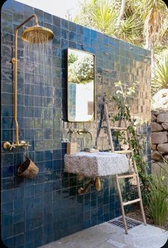 a blue tiled bathroom with a sink and ladder