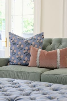 a couch with two pillows on top of it next to a window in a living room