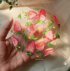 a hand holding a glass plate with flowers painted on the inside and outside of it