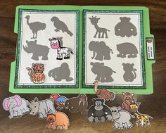 an open book with cutouts of animals on it, sitting on a wooden table