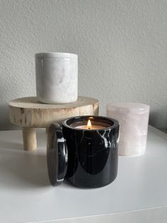 a black candle holder sitting on top of a table next to two white cups and a wooden stand