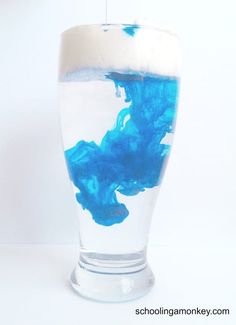 a glass filled with blue liquid on top of a white table