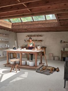 a woman is sitting at a table with buckets on it and a dog laying next to her