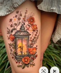 a woman's thigh with flowers and a lantern on it