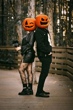 two people dressed up as jack - o'- lanterns on a bridge in the woods