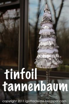 a small silver christmas tree sitting on top of a glass table next to a window