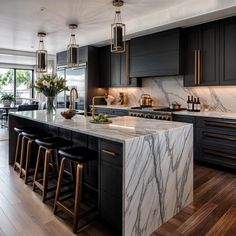 a large kitchen with marble counter tops and black cabinets, along with bar stools