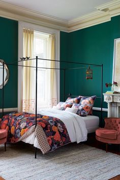 a bedroom with green walls and white bedding in the center is an orange chair