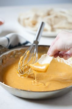 a person is whisking cheese into a bowl with a metal beater on the side