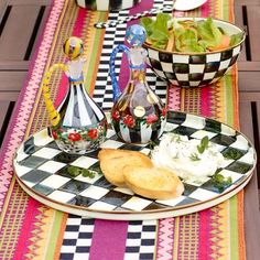 a plate with bread, salad and wine bottles on it sitting on a checkered table cloth