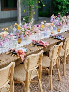 a long table set up with flowers and place settings for an outdoor dinner or brunch