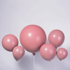 several pink balloons on sticks against a white background