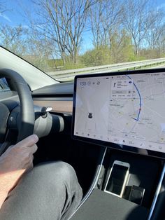 a man driving a car while holding a tablet in his hand with a map on the screen