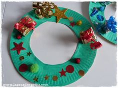 a paper plate christmas wreath with bows and presents on it, next to other crafts