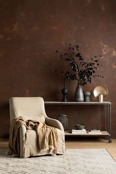 a living room with a chair, table and vases on the wall next to it