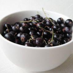 a white bowl filled with black berries on top of a table