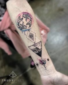 a person with a tattoo on their arm holding up a small piece of artwork that is in the shape of a triangle