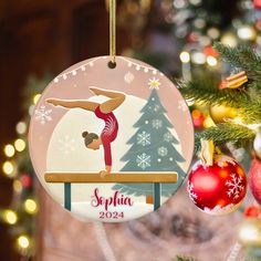 a christmas ornament with a girl doing a gymnastics trick on the balance beam