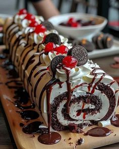 a cake with oreo cookies and cherries on it is sitting on a wooden board