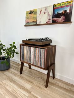 a record player sitting on top of a wooden cabinet next to a potted plant