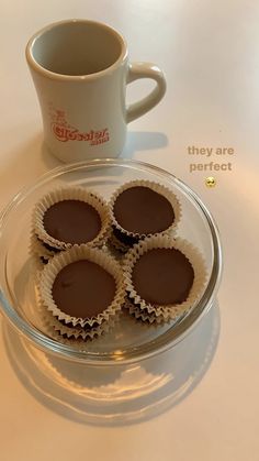 four chocolate cups on a glass plate next to a coffee cup and saucer that says, they are perfect