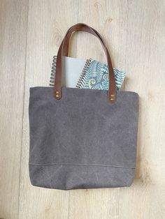 "Moon gray canvas tote with brown leather straps This tote bag is a perfect size to carry all your essentials for the day. It is cute and stylish and will last for years and years.  It is made with beautiful and durable stone washed canvas in moon gray. The straps are brown leather.  The lining has two slip pockets and a magnet snap to hold closed. It measures 16.5\" wide at the top 12.5\" wide at the bottom 13\" tall 4.5\" deep strap drop is 10\" Please let me know if you have any questions" Canvas Tote Bag With Leather Trim, Brown Cotton Canvas Bag With Leather Handles, Gray Bags With Leather Handles For Daily Use, Gray Canvas Tote Bag, Waxed Canvas Tote Bag For Daily Use, Gray Bags With Leather Handles For Everyday Use, Gray Canvas Shoulder Bag With Leather Handles, Everyday Large Capacity Gray Canvas Bag, Gray Bags With Leather Handles