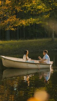 a man and woman are sitting in a small boat on the water near some trees