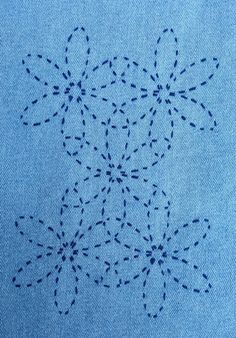 a blue piece of cloth with small black dots on it and an embroidered design in the middle