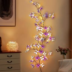 purple and white flowers are lit up on the wall