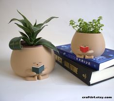 two planters sitting on top of each other next to books with plants growing out of them