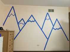 a room with mountains painted on the wall and dressers in front of it,