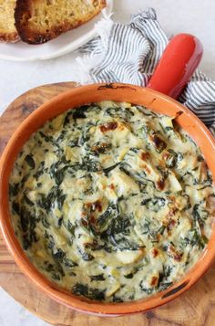 an orange bowl filled with spinach and cheese