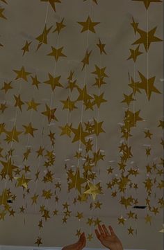 two hands reaching up to the ceiling with gold stars hanging from it's sides