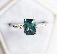 an emerald colored ring with two white diamonds