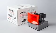 a red and black object sitting next to a box on a white surface with the words bly - 1001 printed on it