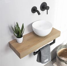 a white bowl sitting on top of a wooden shelf next to a potted plant