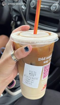 a woman holding up a drink in her hand with a sticker on the lid