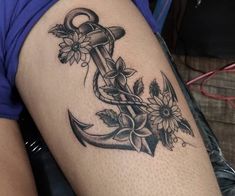 an anchor tattoo with flowers on the thigh