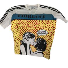 The Adidas X Fiorucci Graphic T-Shirt Include: Rib Crew Neck With Interior Tape Fiorucci Artwork Printed On Front 3 Stripes Tapes On Shoulders And Sleeves Adidas Trefoil Logo Printed At Top Rear Loose Fit 73% Cotton, 27% Nylon Jersey (Better Cotton Initiative Designer Multicolor Graphic Print Tops, Designer Fitted T-shirt With Graphic Print, Designer Graphic Print T-shirt For Spring, Designer Yellow Short Sleeve Tops, Adidas Tops With Logo Print For Spring, Adidas Multicolor Graphic Print Tops, Adidas Multicolor Graphic Print T-shirt, Fitted Adidas T-shirt For Spring, Random Clothing