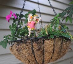 a hanging planter filled with plants and fairy figurines