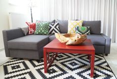 a living room with a gray couch and red coffee table