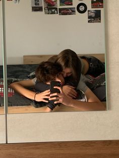 two people are hugging in front of a mirror