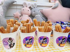 several cups filled with french fries sitting on top of a checkered table cloth next to stuffed animals