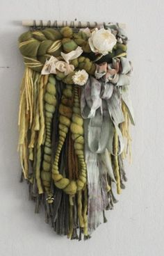 a piece of art made out of different types of yarns and flowers hanging on a wall