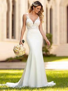 a woman in a white wedding dress walking through the grass with her bouquet on her hand