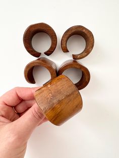 a hand holding a wooden object with four rings on it