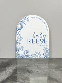 a blue and white sign that says baby reese on it's front with flowers in the background